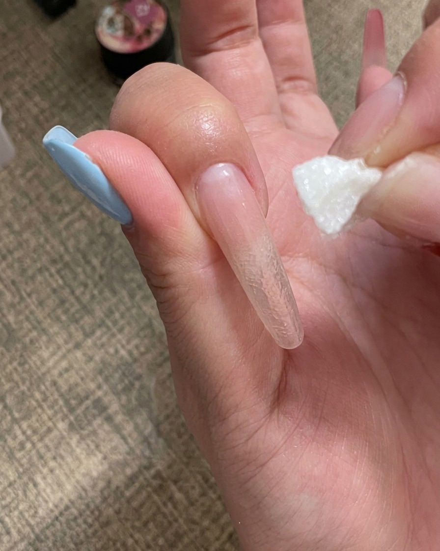 A hand placing a nail under a mini portable UV lamp.