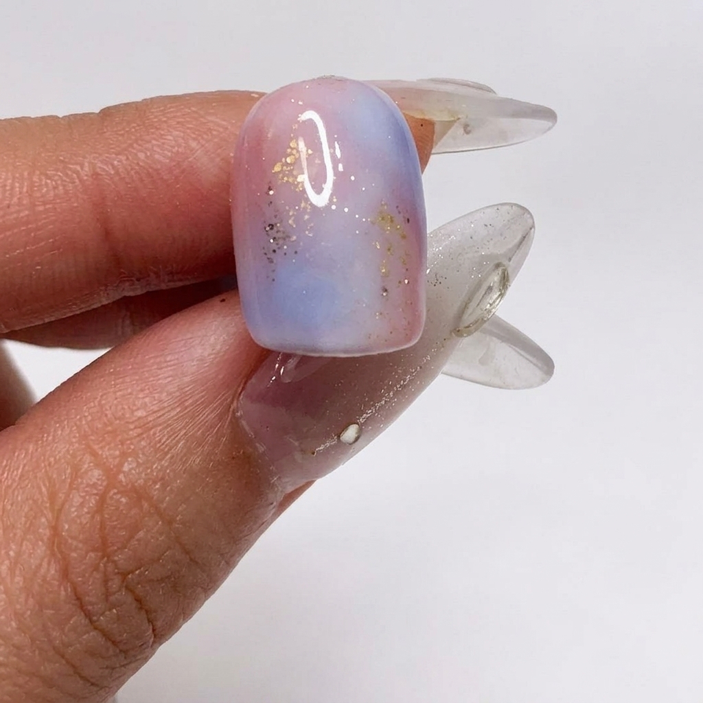 A brush applying a matte top coat over the textured, glitter-infused gradient nail.