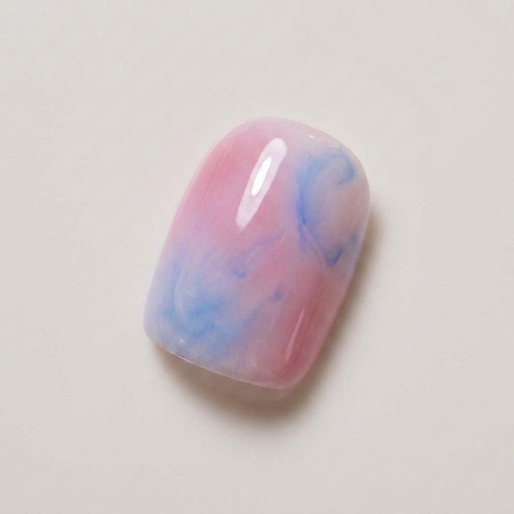 A nail showing a soft blended mix of nude pink and light blue gel polish.