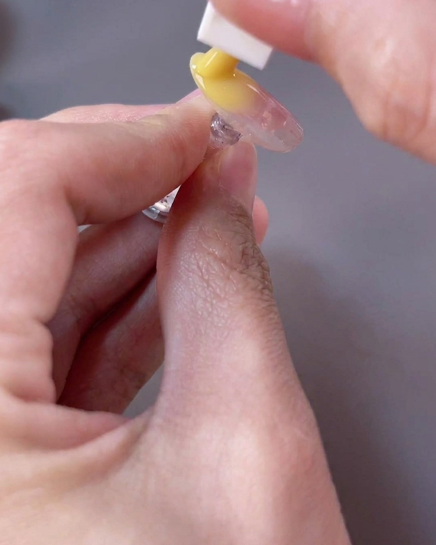 A sponge tool dabbing a bright yellow gel onto the free edge of the nail to create a gradient effect.