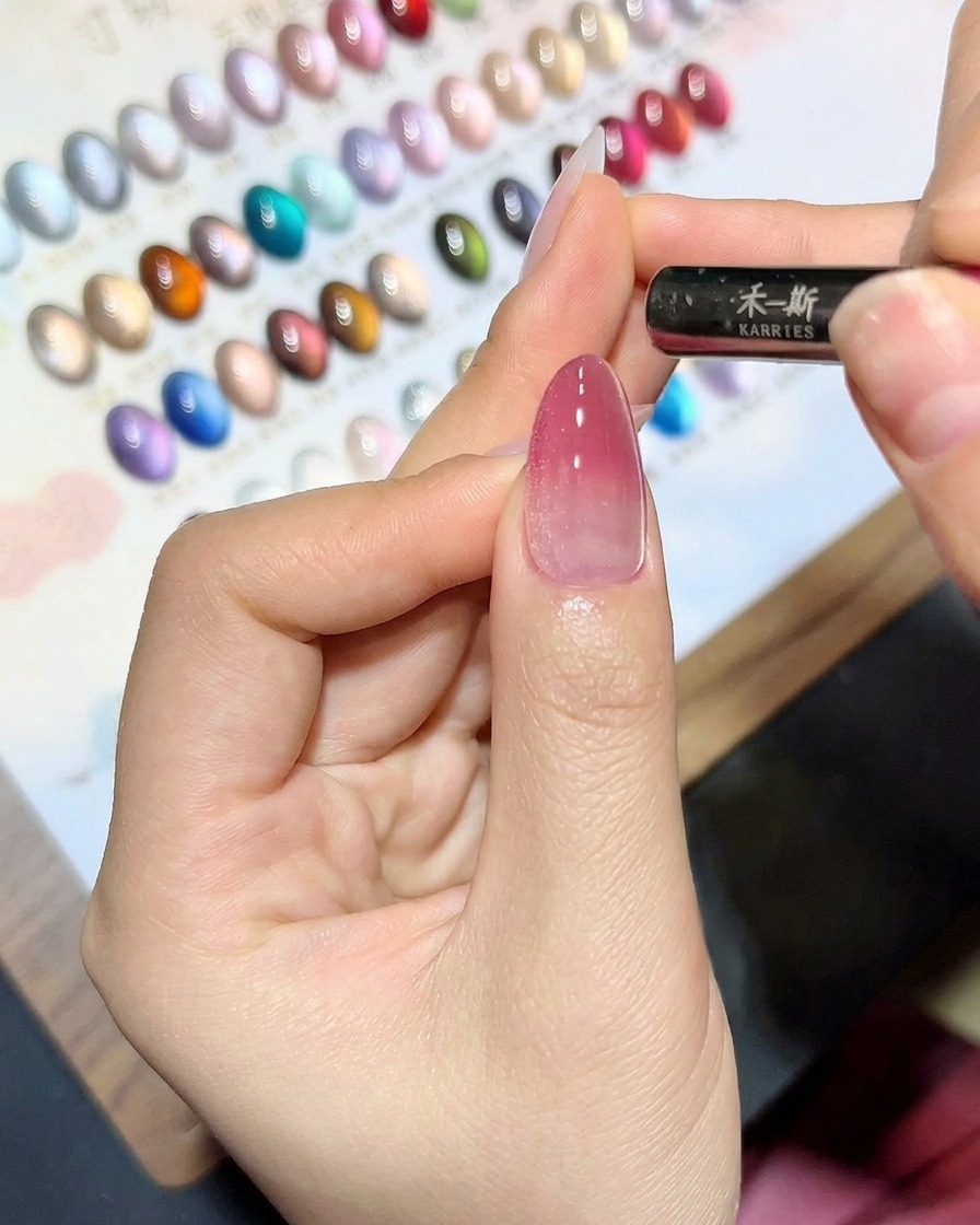 A magnetic tool being held close to a nail coated in cat-eye gel to create a shimmer line.