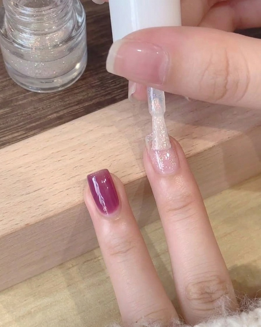 A close-up view of a shimmering, polarized top coat being applied over a deep purple gel base.