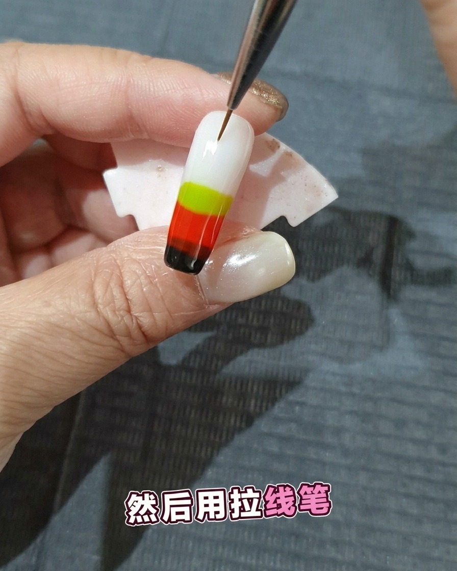 A fine-detail nail art brush dragging through multiple layers of wet colored gel polish to create a flame pattern.
