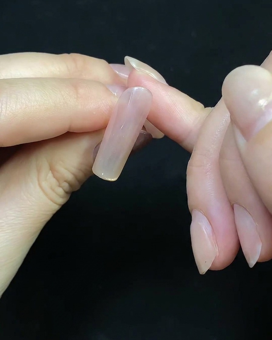 A fine liner brush drawing delicate red lines on a nail tip to outline a firework design.