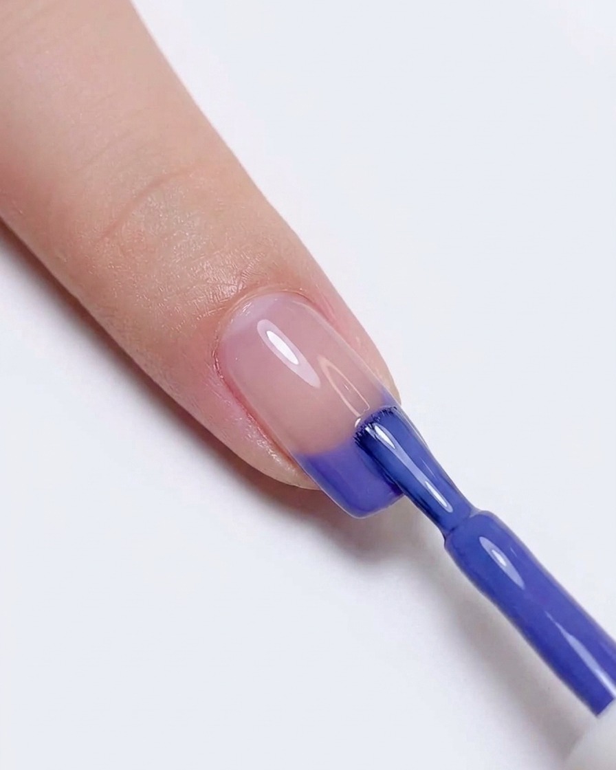 Re-applying blue and purple gel polish to the tip of the nail to intensify the color transition.