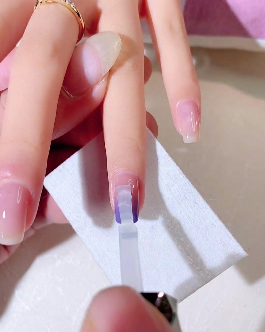 A clear gel brush blending the second layer of gradient color downwards on the nail.