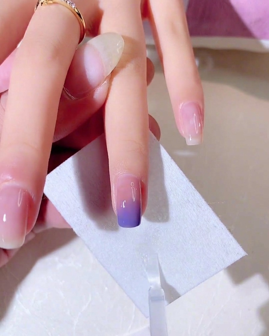 A thin metallic silver line being drawn across the tip of the nail to create a French-style border.