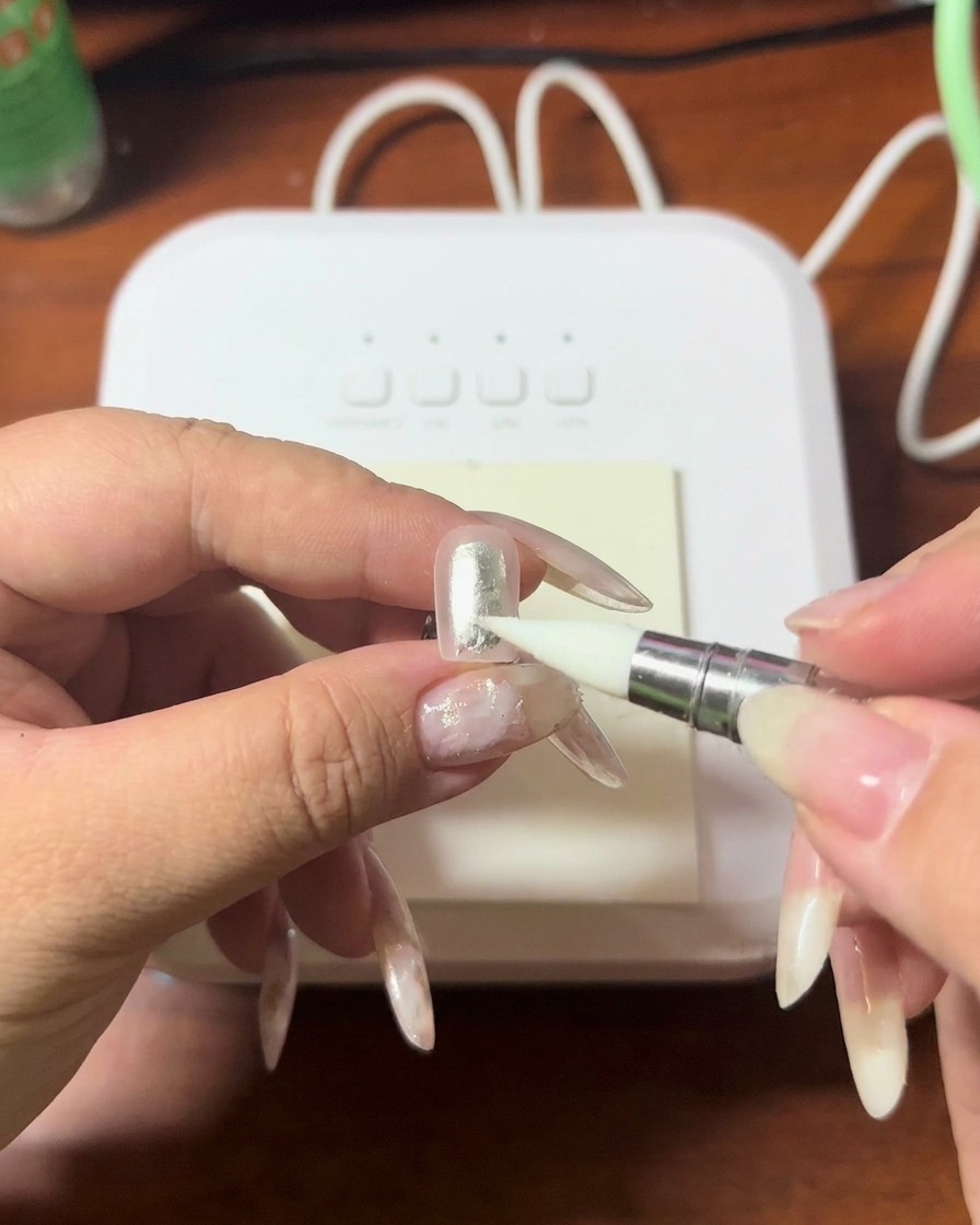 A close-up of a silicone tool pressing gently onto the tip of a nail to blend gel.