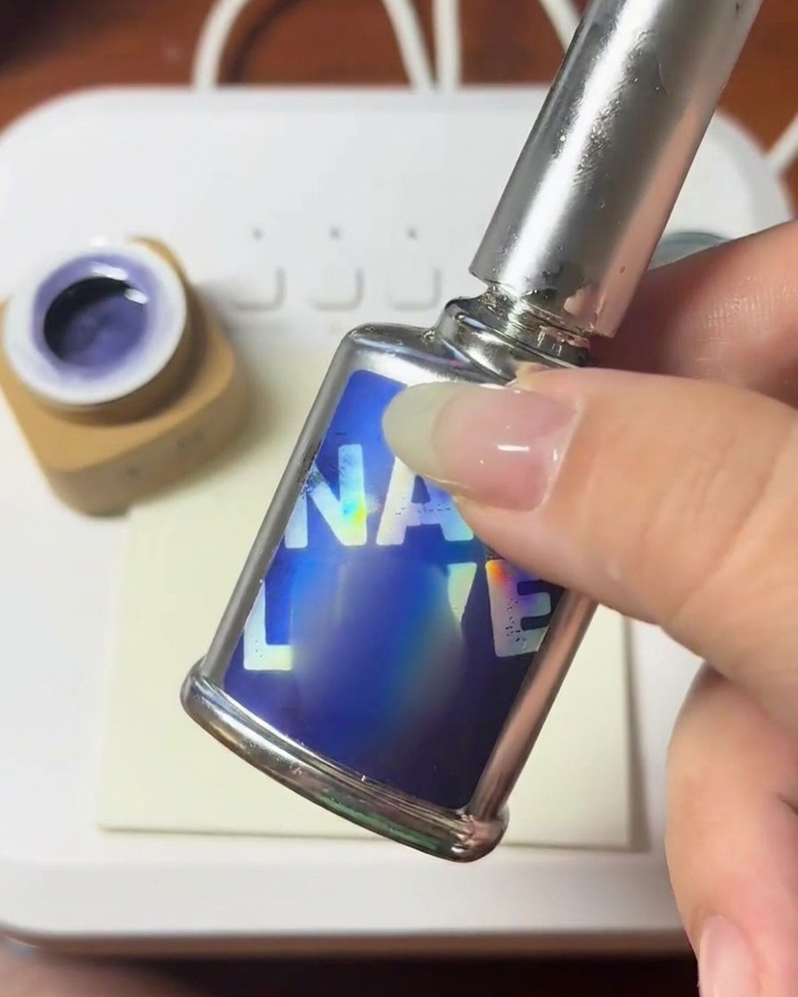 A brush applying a clear, viscous bead of builder gel onto the surface of a nail.