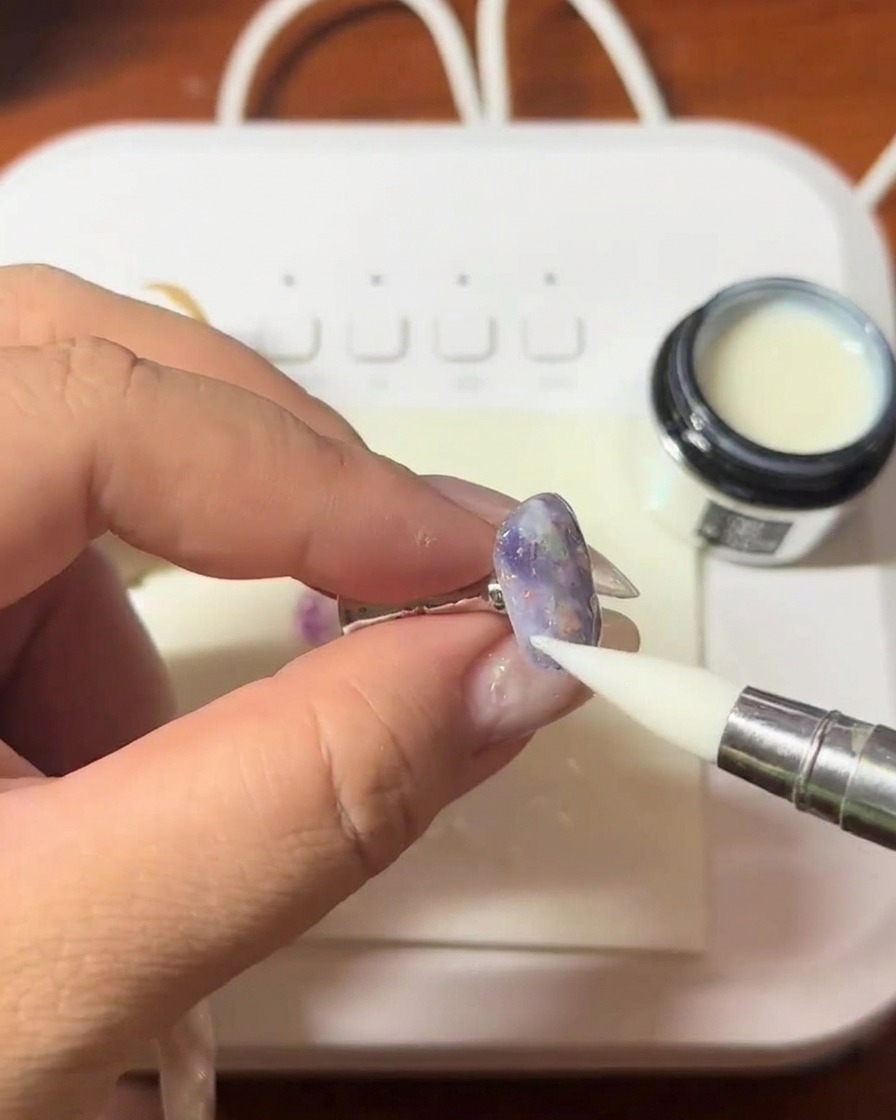 A layer of clear, thick builder gel being applied to the nail surface with a brush.