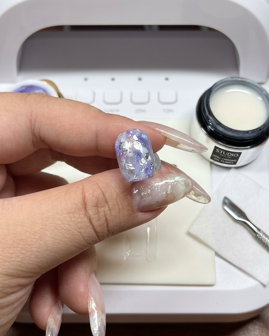 A brush being used to blend and blur the edges of white gel on the nail.
