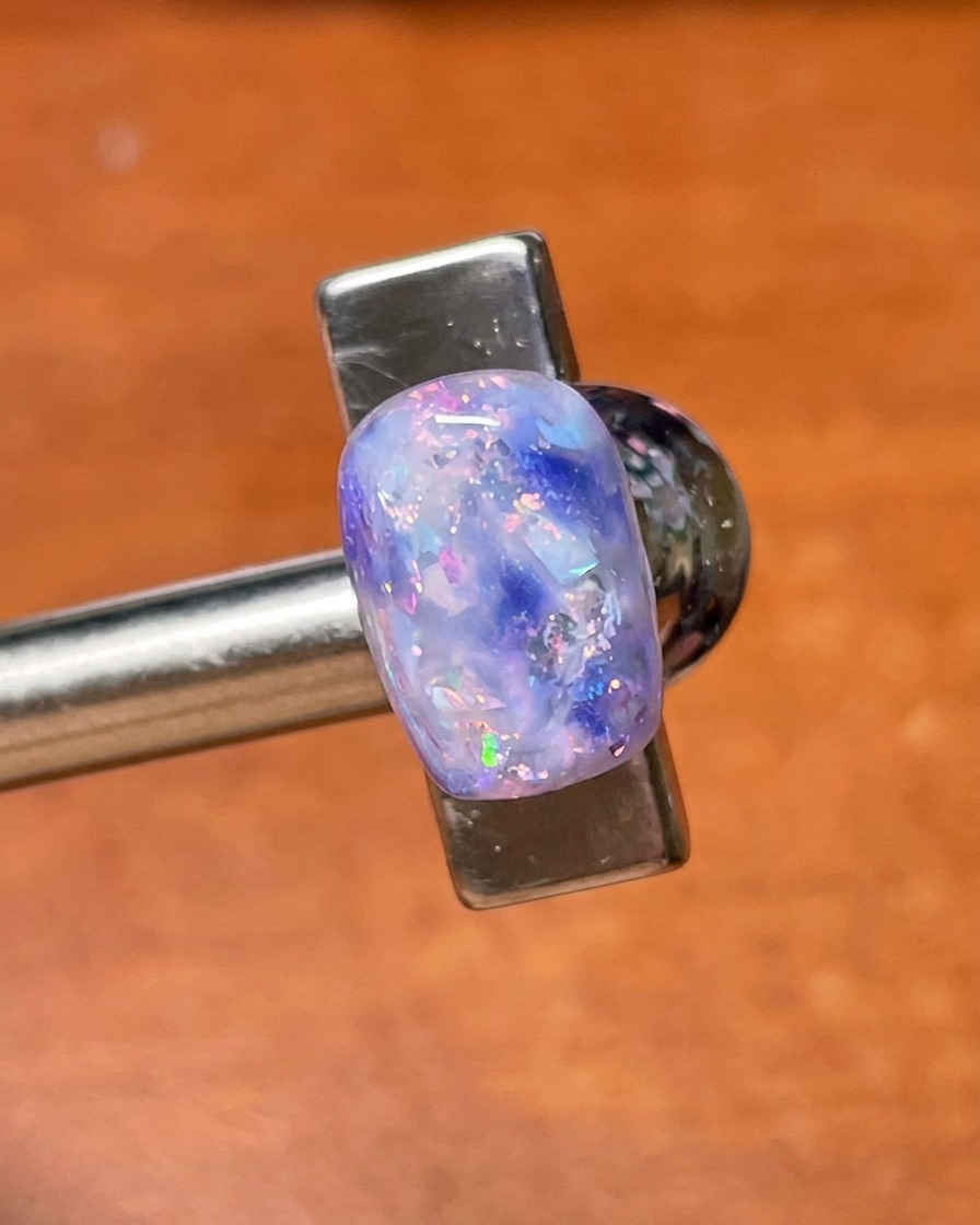 A top coat brush applying a final sealing layer over the finished purple shell and glitter nail art.