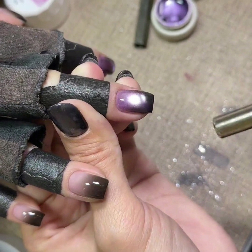 Nails with purple cat eye gel being cured under a UV lamp, with the glow from the lamp visible.