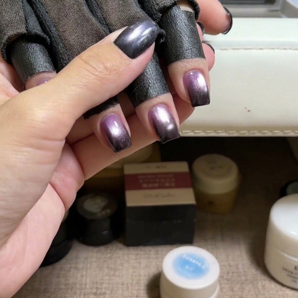 A brush applying blue cat eye gel polish onto a natural fingernail.