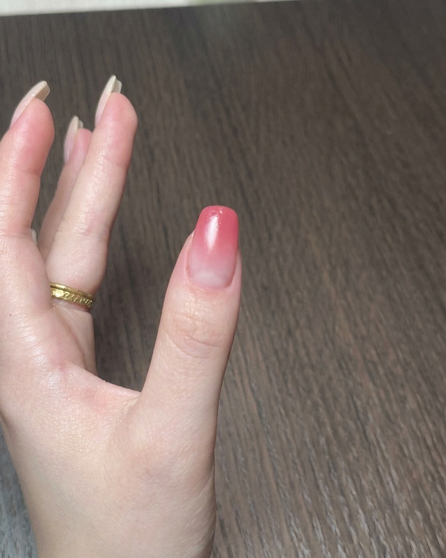 A miniature portable lamp curing gel polish on a fingernail.