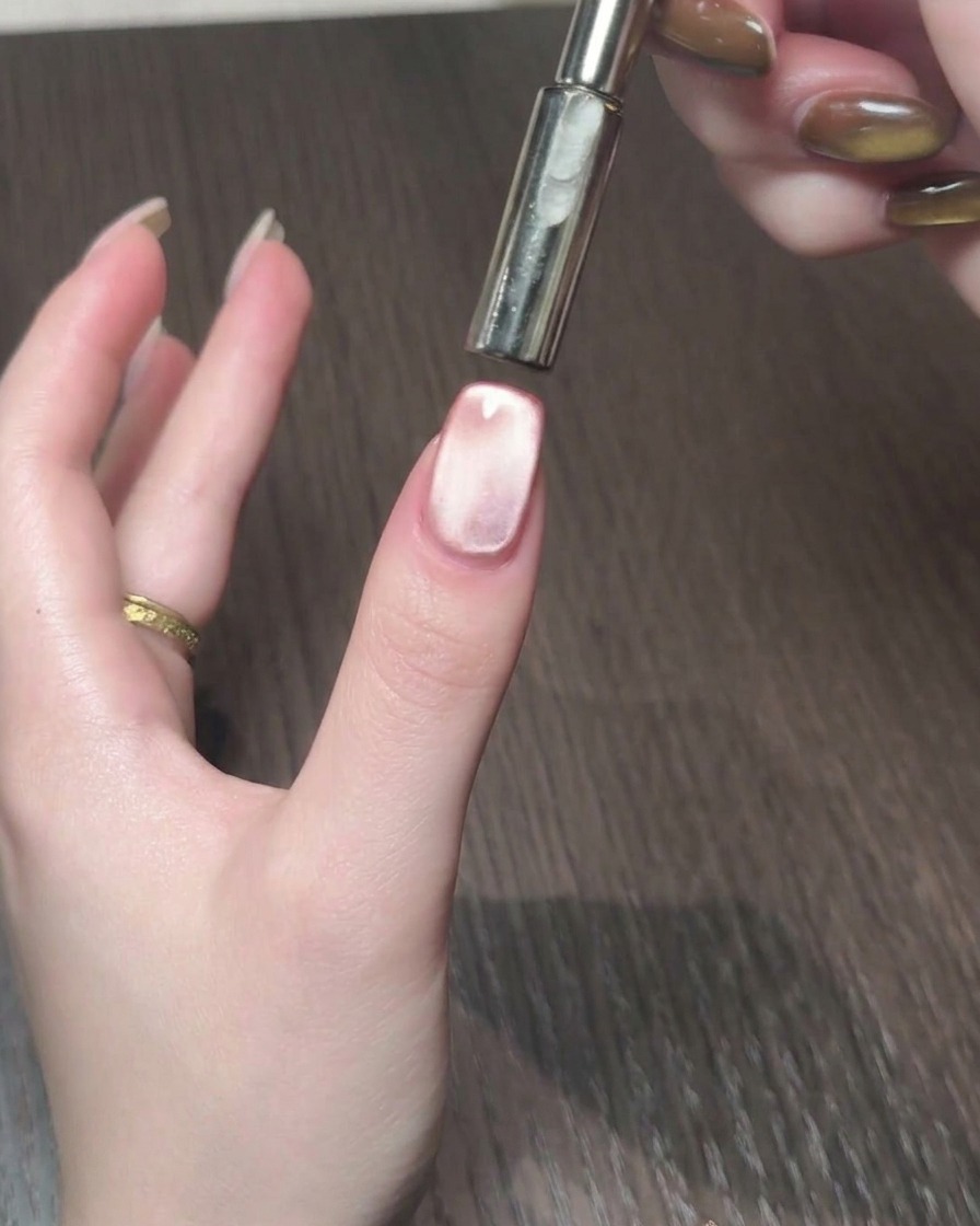 A magnetic tool being used to manipulate the cat eye shimmer into a luminous band on the nail.