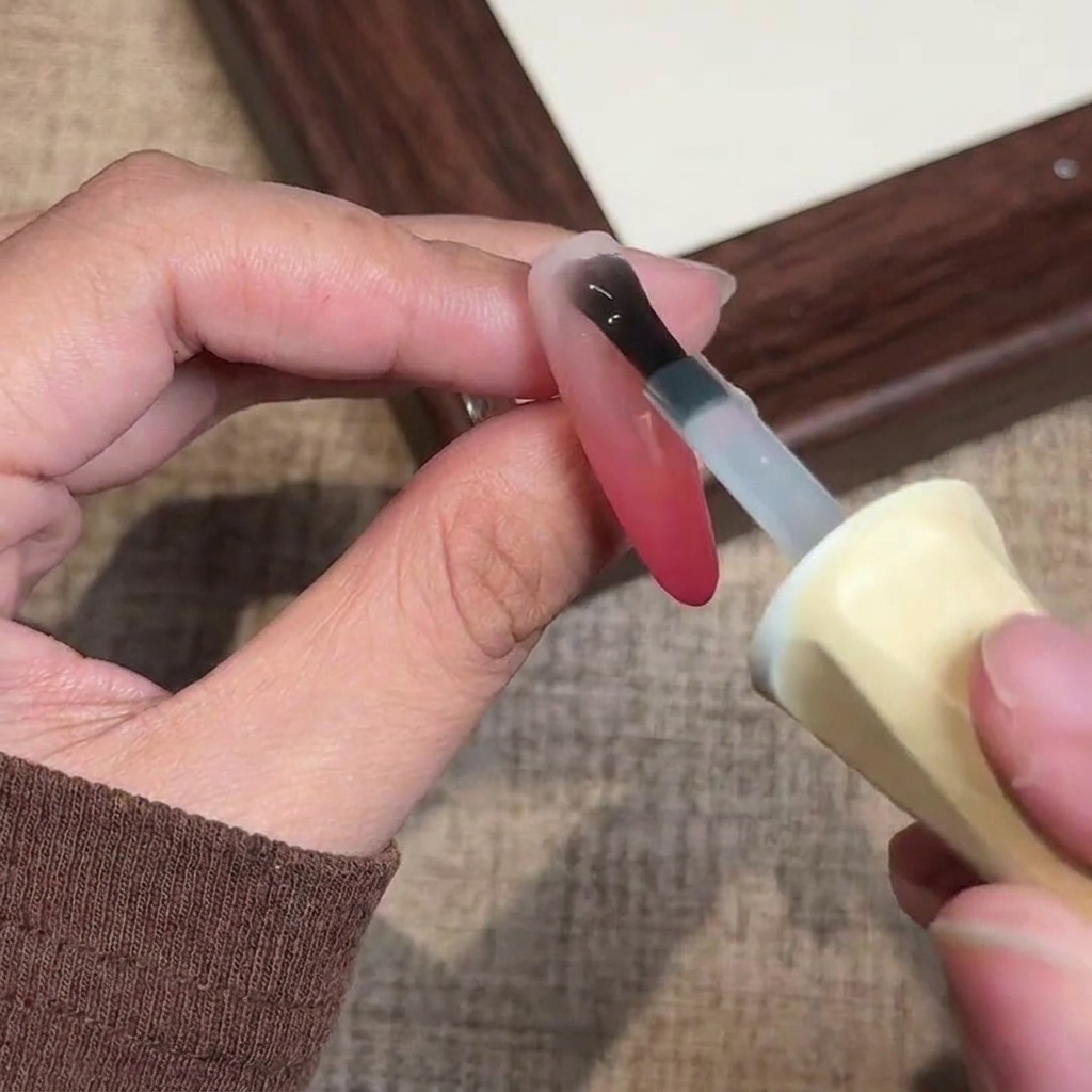 A brush applying a final coat of clear matte gel top coat over the finished ombre nail.
