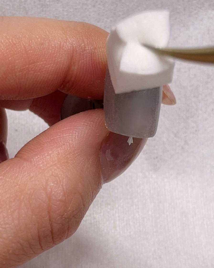 A close-up view of a sponge blending blue gel polish on a nail to create an ombre effect.