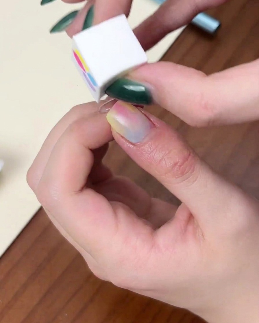 A fingernail placed inside a red dome-shaped UV/LED lamp while the purple light is on.