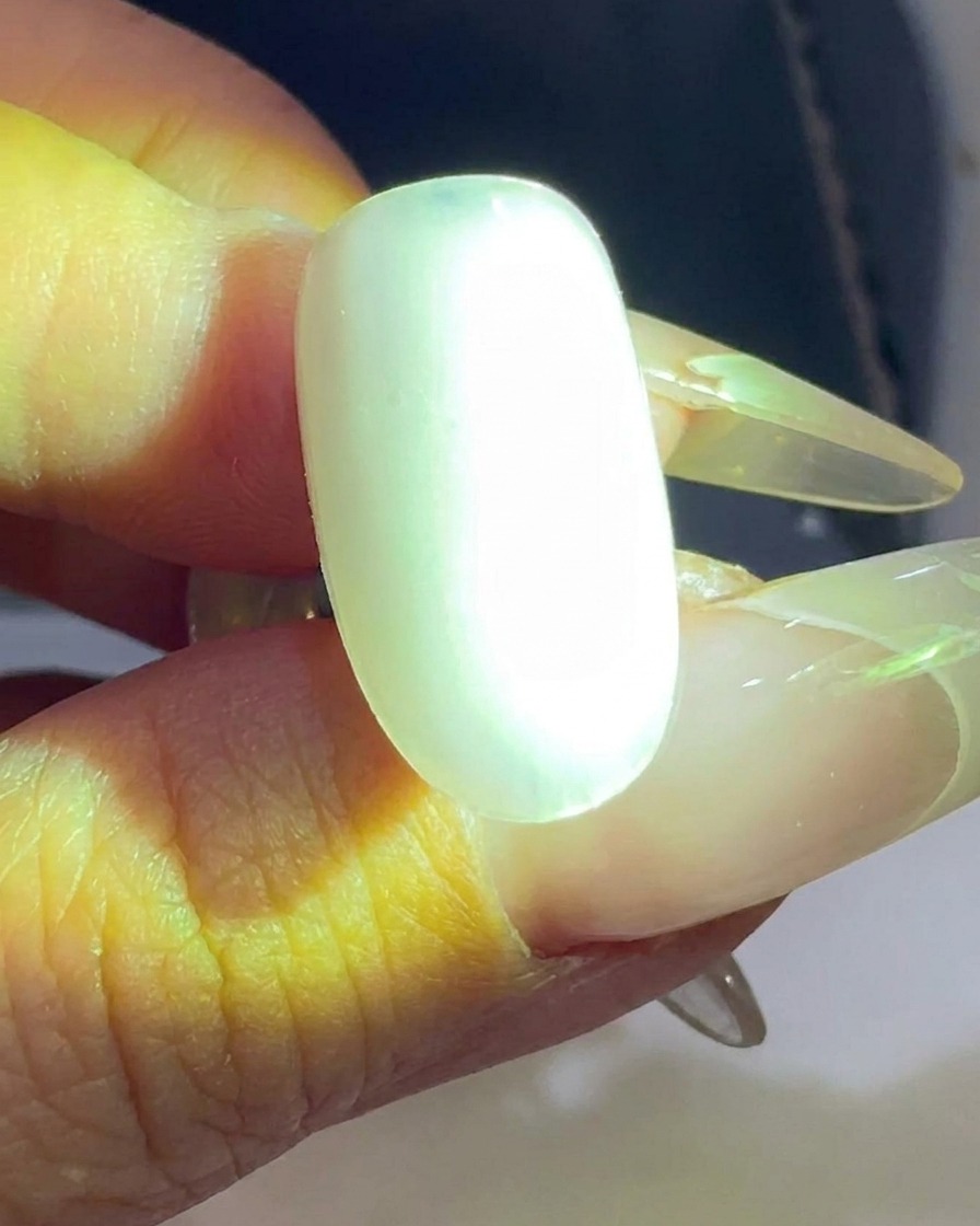 A clear nail tip being cured under a UV/LED nail lamp.
