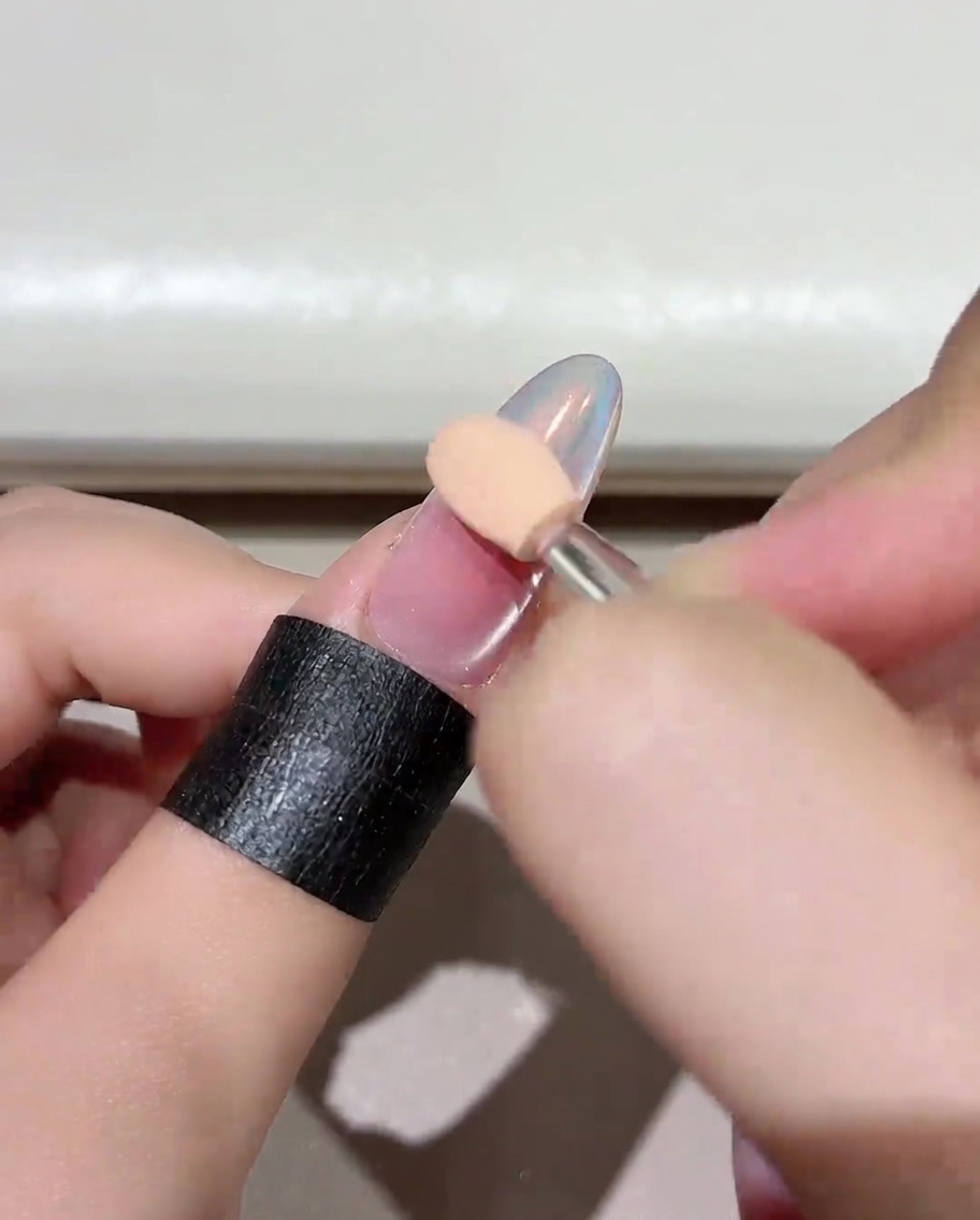 A close-up of a manicured nail placed inside a professional UV/LED nail lamp, showing the curing process.