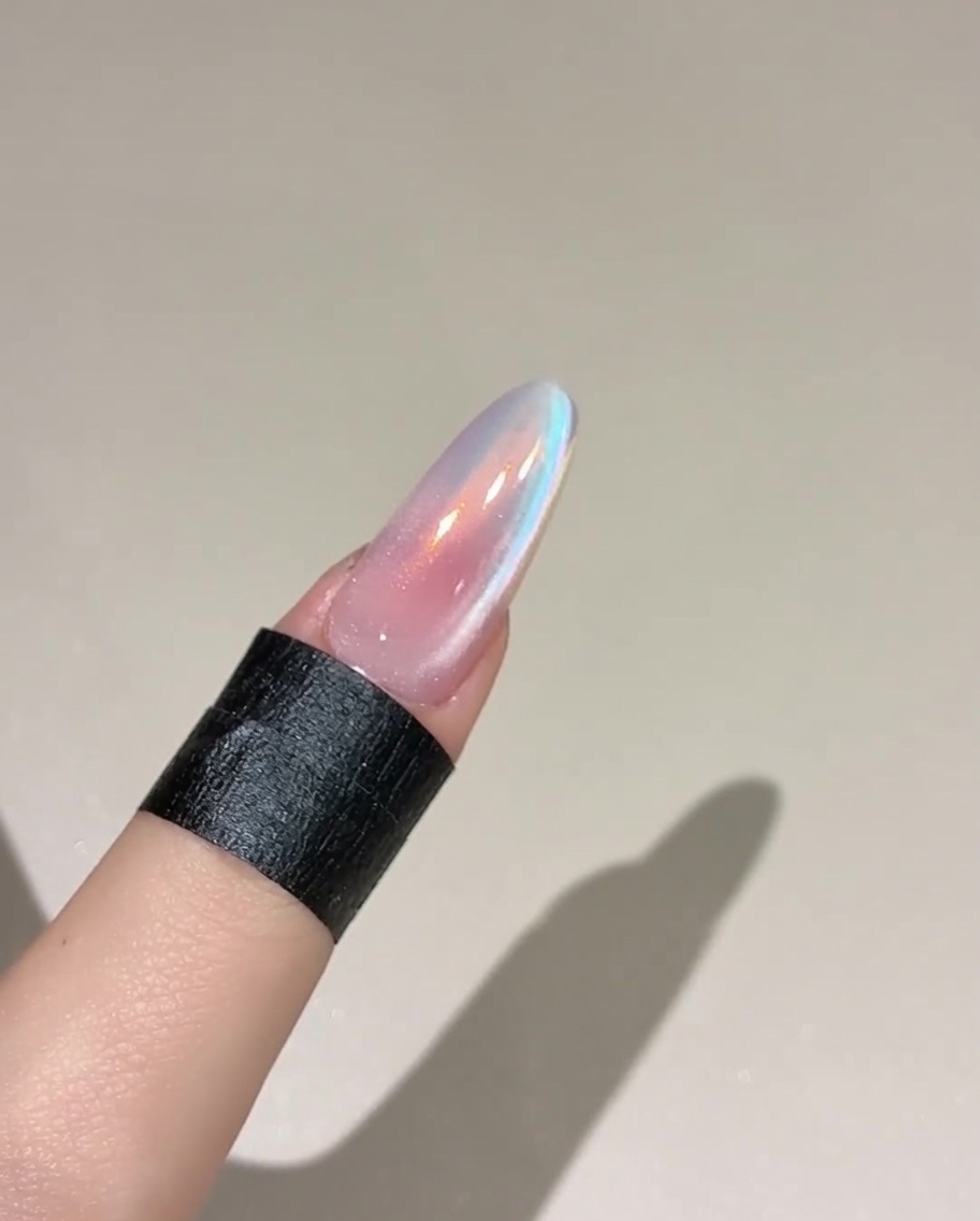 A brush applying a coat of top gel over a pink, cured nail.