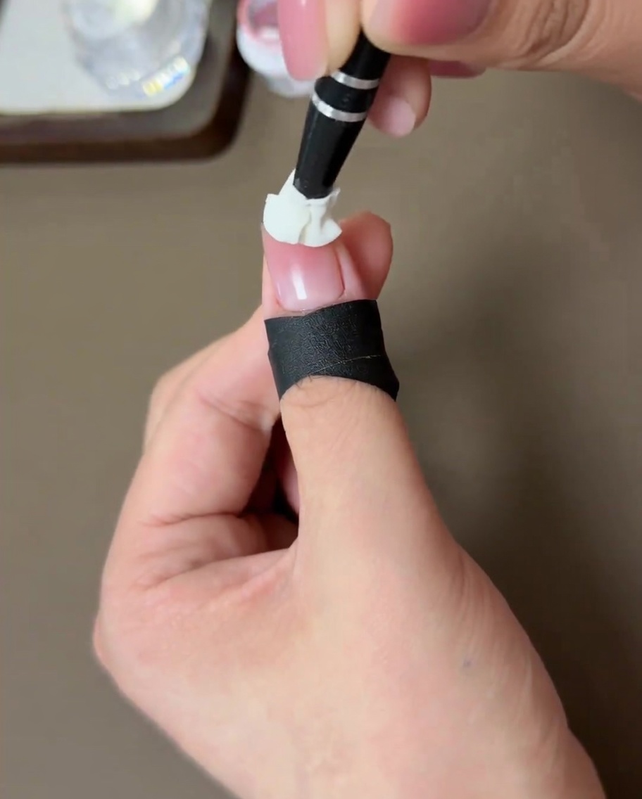 A nail with a peach blush effect curing inside an LED lamp.