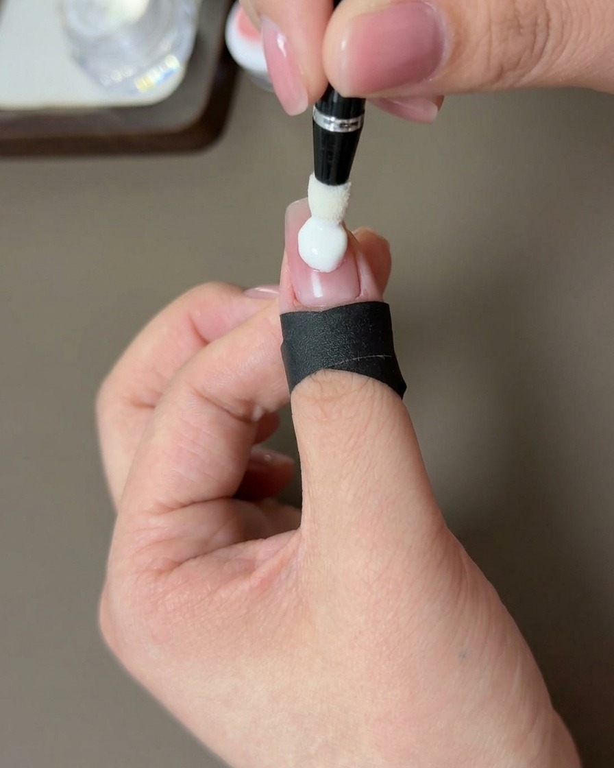 A close-up view of a hand with a peach-blushed nail tip being cured under a professional UV lamp.