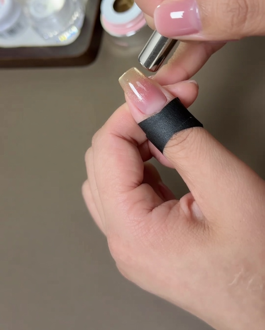 A cylindrical magnet being held near the sides of a nail to move the gold magnetic particles.