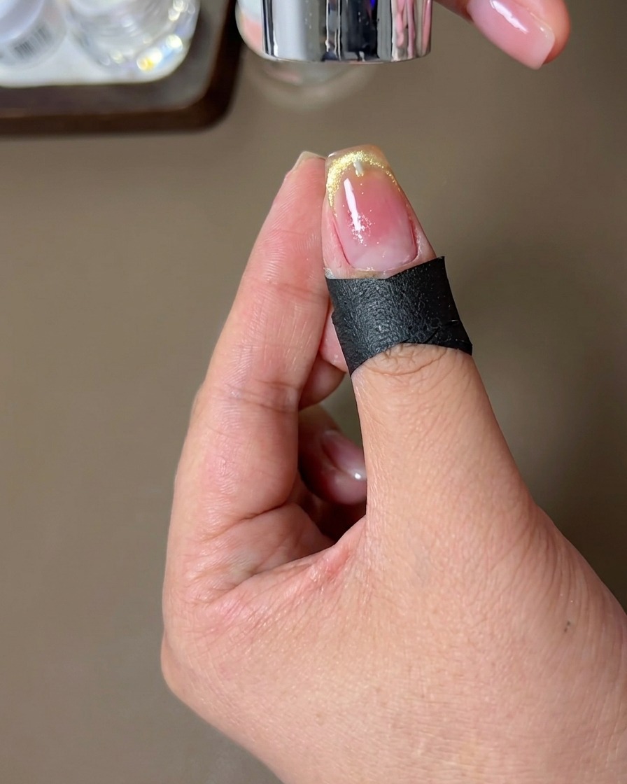 A nail with the finished magnetic French-tip design being cured under a nail lamp.