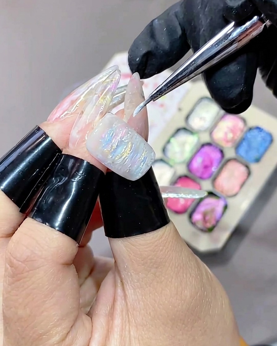 A fine-tipped brush applying white highlighting gel to the textured surface of a gel manicure.