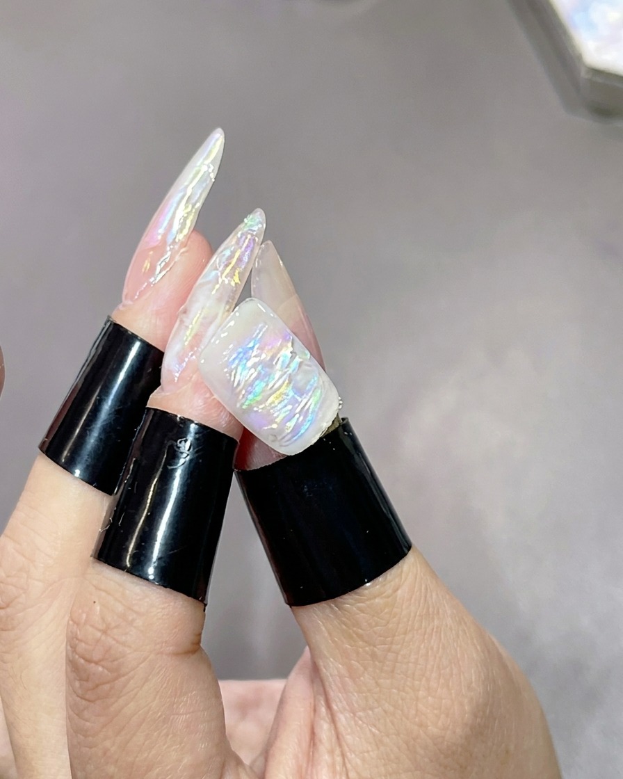 A hand with textured, marbled nails resting inside a UV curing lamp to set the highlight layer.
