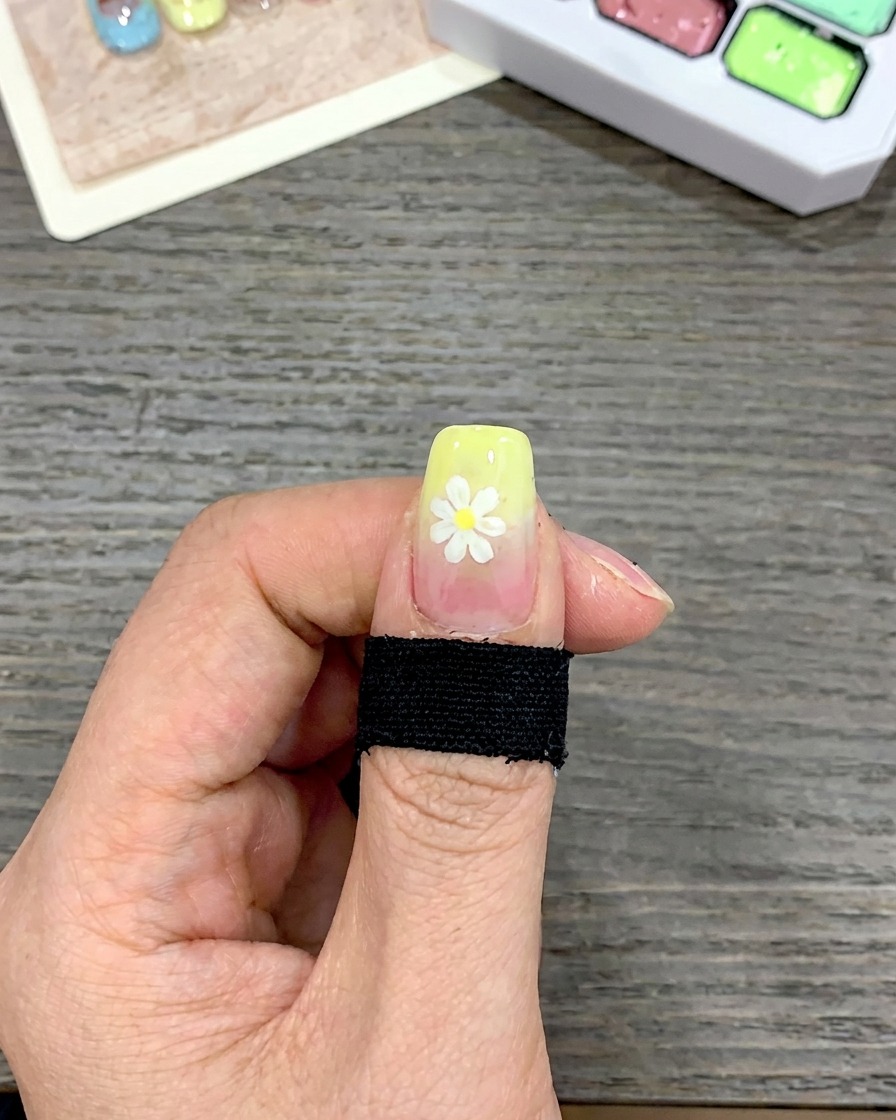 A close-up of a nail with a thick layer of yellow gel polish applied to the tip using a square-tipped brush.
