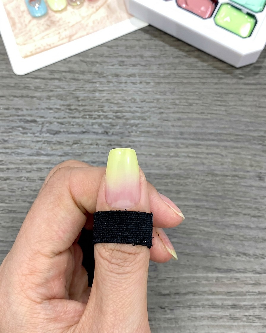 A close-up showing a smooth yellow-to-clear gradient on a fingernail created by tapping with a sponge.
