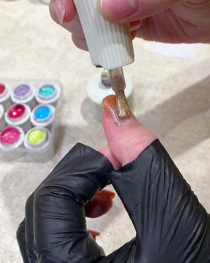 A magnet being held over a wet gel nail to shift the magnetic particles into a glowing stripe.