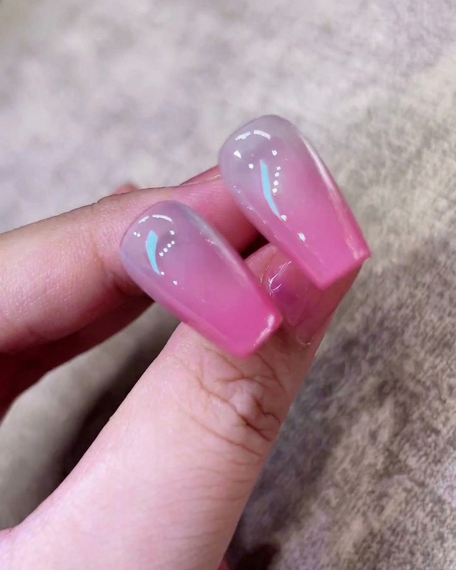 A sponge being pressed onto a nail tip to create a soft pink ombre gradient.