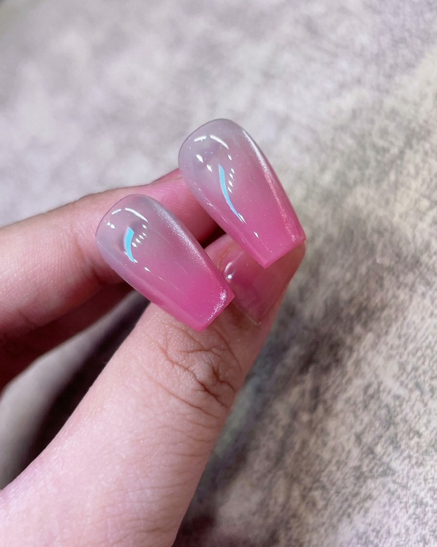A magnet tool held near a nail to shift the shimmering particles into a concentrated cat-eye streak.