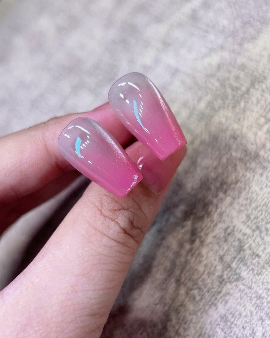A sponge reapplying concentrated pink pigment to the very end of the nail tip.