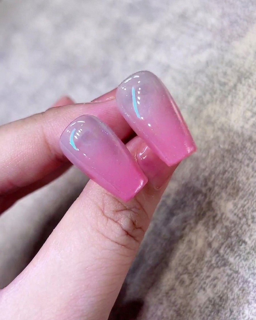 A final pass of shimmering cat-eye polish being applied to the nail to perfect the finish.
