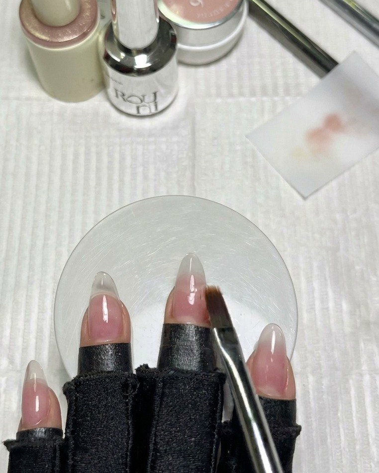 A clean flat gradient brush softly blending the milky white polish edge on an adjacent fingernail.
