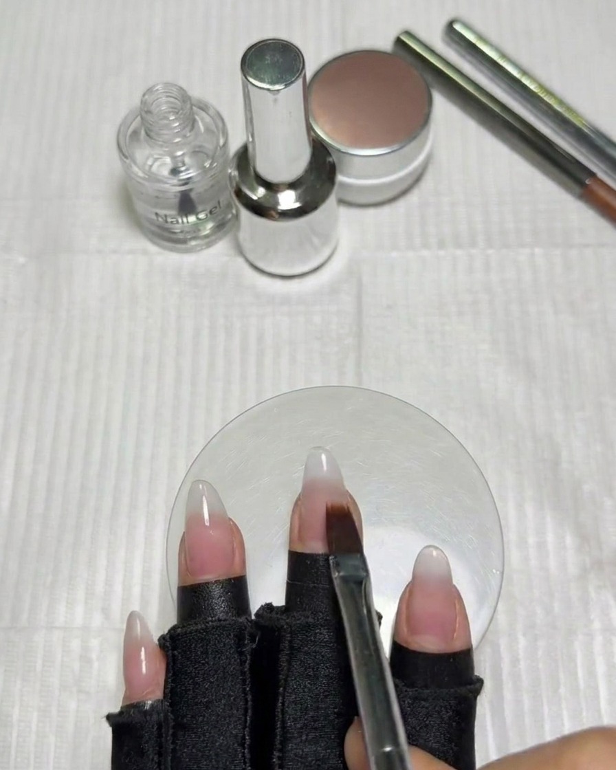 A hand with gradient nails positioned inside a UV/LED lamp for curing.