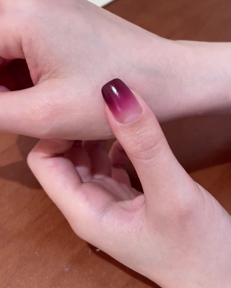 A hand with a gradient base coat placed inside a professional UV nail lamp for curing.