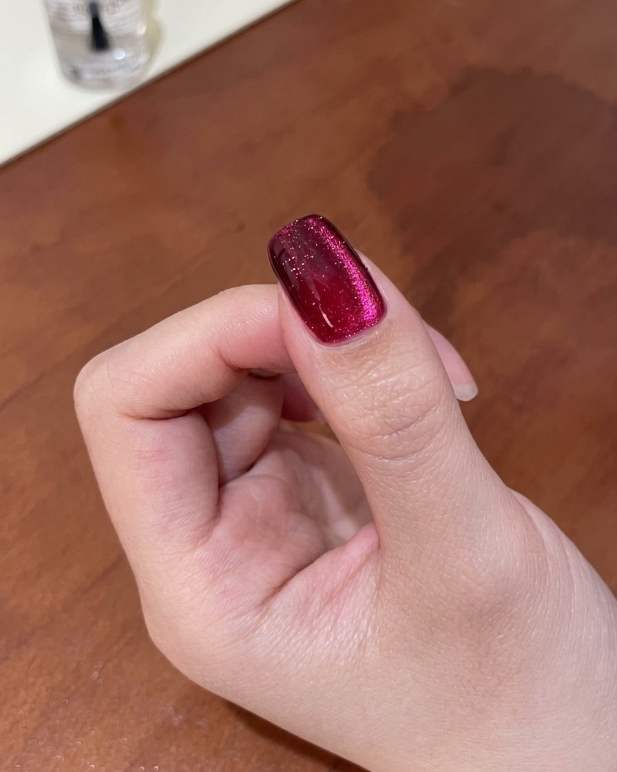 Close-up of a nail showing the magnetic shimmer being refined into a deep, gradient cat-eye look using a magnet.