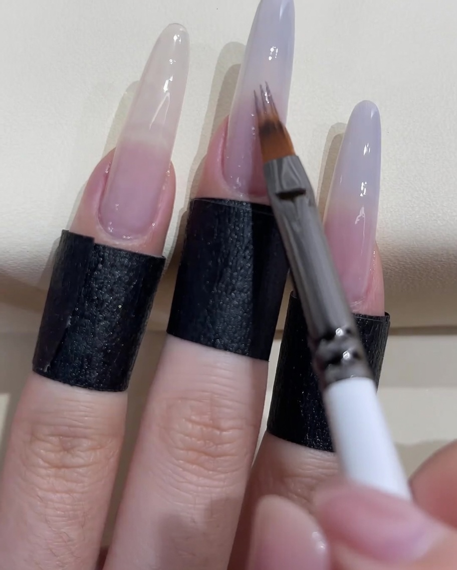 A specialized ombre brush blending the grey-blue polish downwards on the nail.