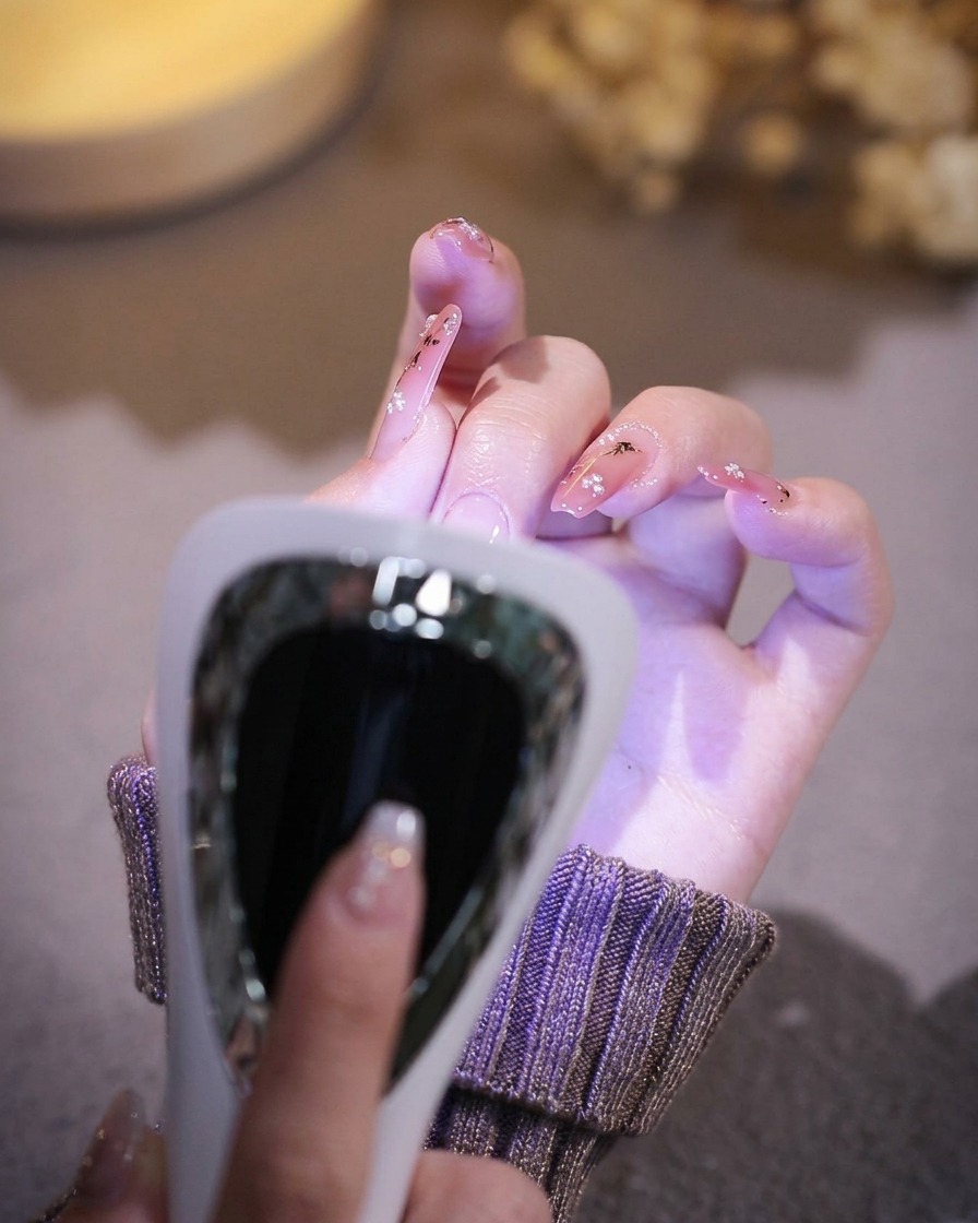A hand resting inside a professional UV/LED nail lamp with the light activated.
