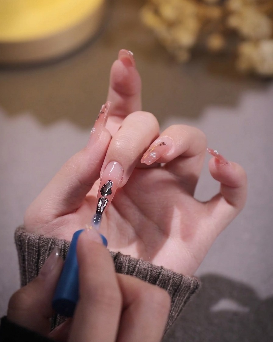 A brush applying a second thin coat of sheer pink gel over the first cured layer.