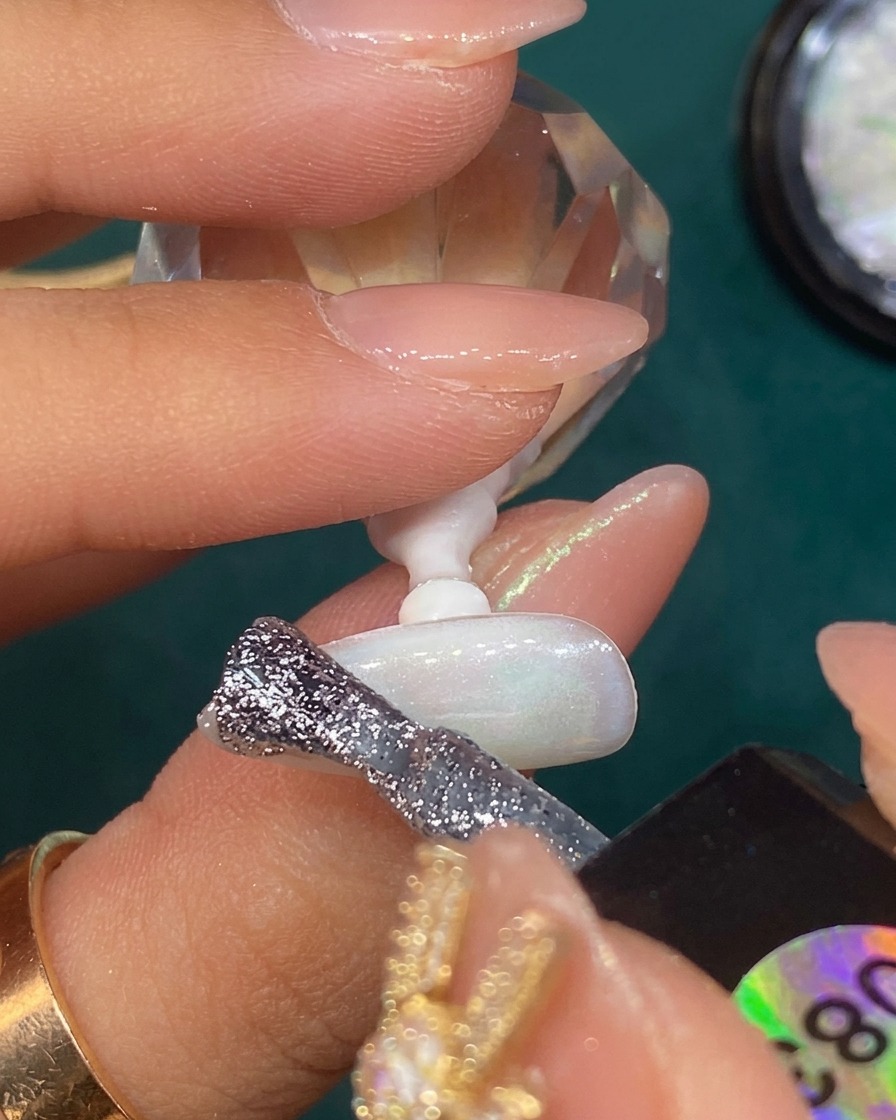 Silver glitter gel being blended into a gradient on the tip of a translucent white nail.