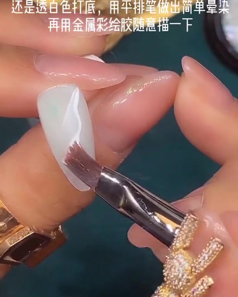 A flat nail brush being used to blend wet white gel polish on a nail surface.