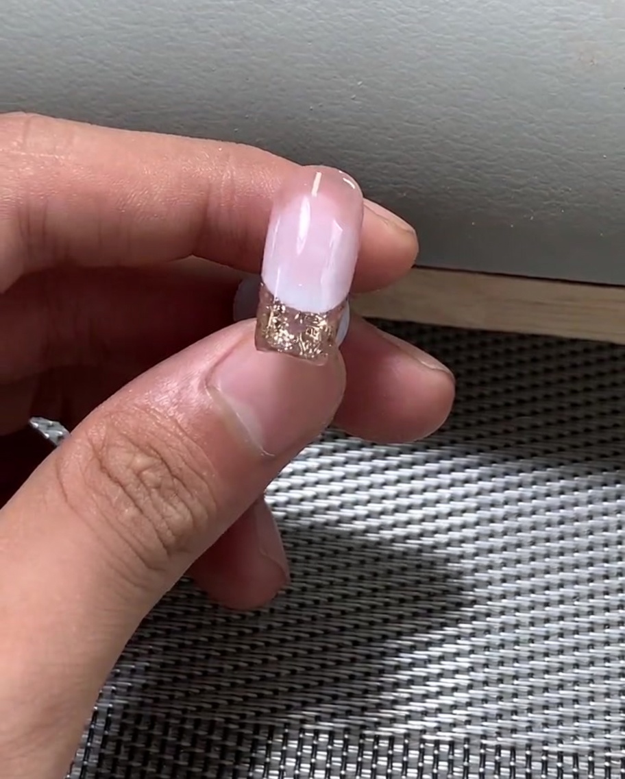 A hand positioned under a professional UV nail lamp curing the gel polish.