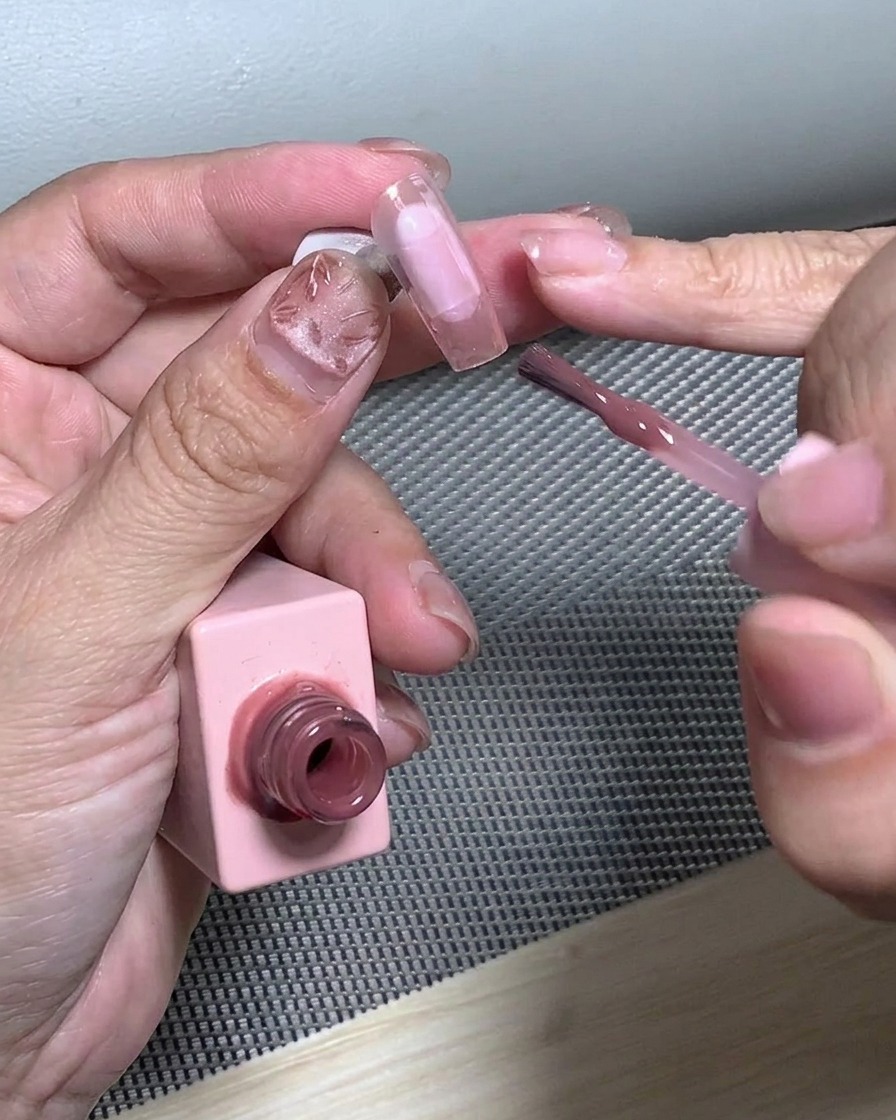A brush blending glitter on the nail tip to form a gradient effect.